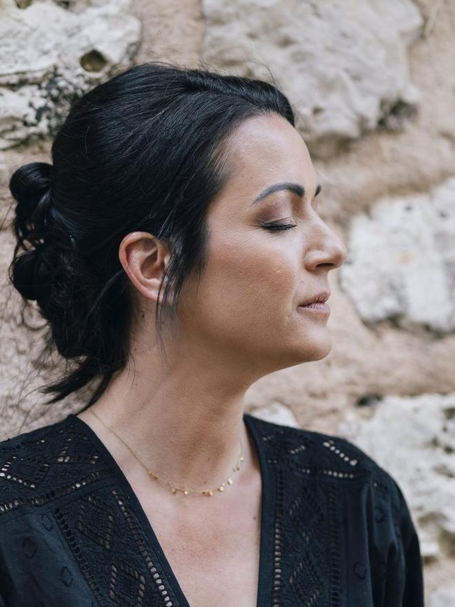 Portrait de profil devant un mur de pierre, chignon bas : teint lumineux, pommette sculptée et paupière nude