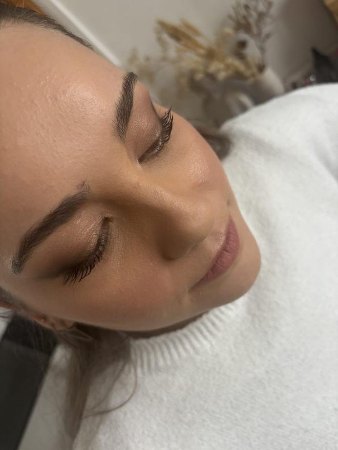 Gros plan sur un teint travaillé pour la photographie : peau lumineuse, sourcils redessinés et cils recourbés, bouche rosée