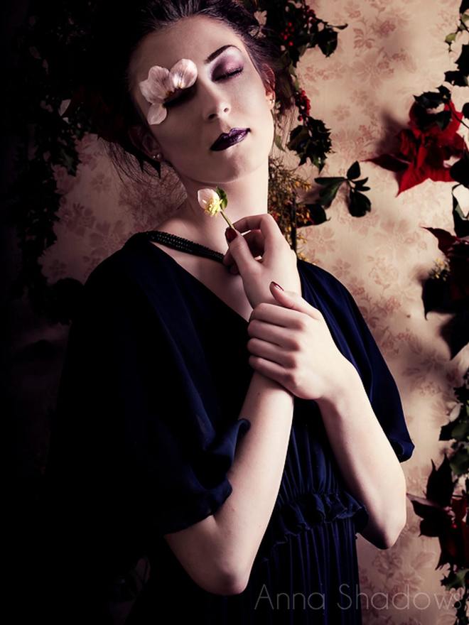 Portrait éditorial sur fond de fleurs séchées, paupières nacrées et bouche sombre, maquillage construit pour une série photographique